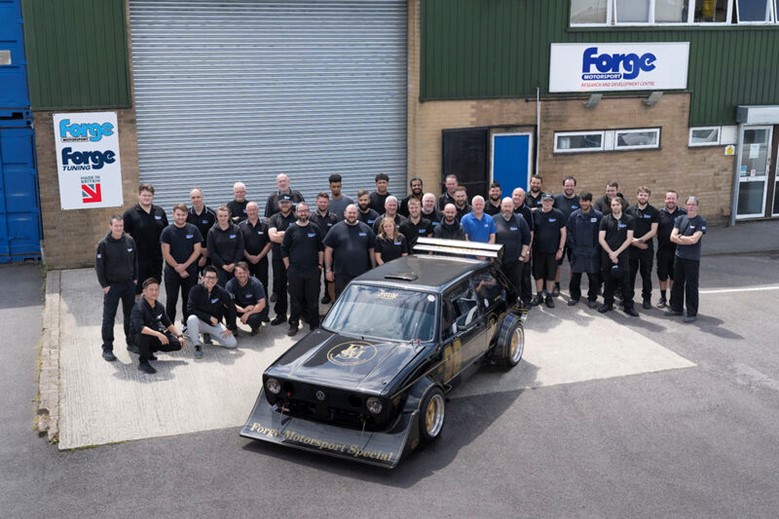 an aerial photo of Forge factory and all the employee outside lined up for a photo with one of their cars in front of them